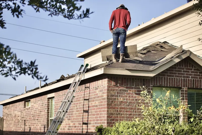 Professional roofer working on a residential roof in Poquott